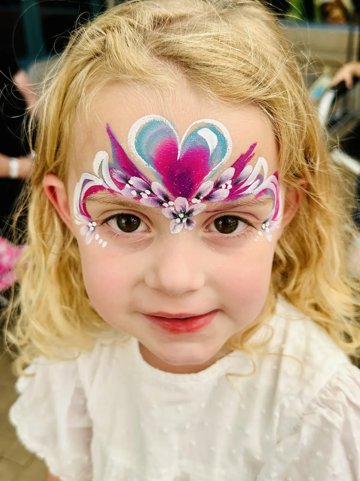 Child with pink princess mask face painting.