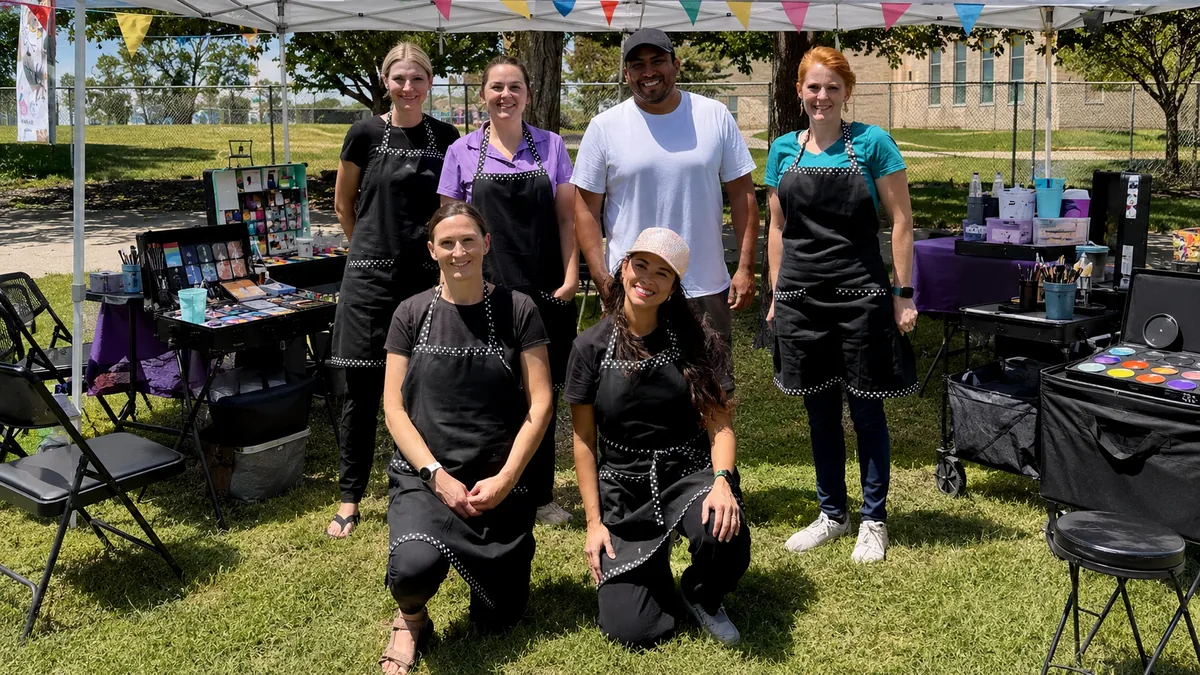 Colory Faces team members at an outdoor event booth.