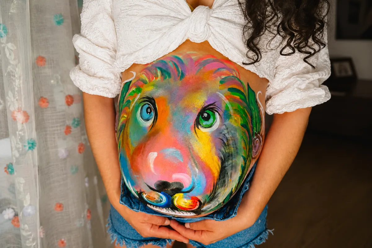 Colorful lion belly painting design for a pregnancy celebration.