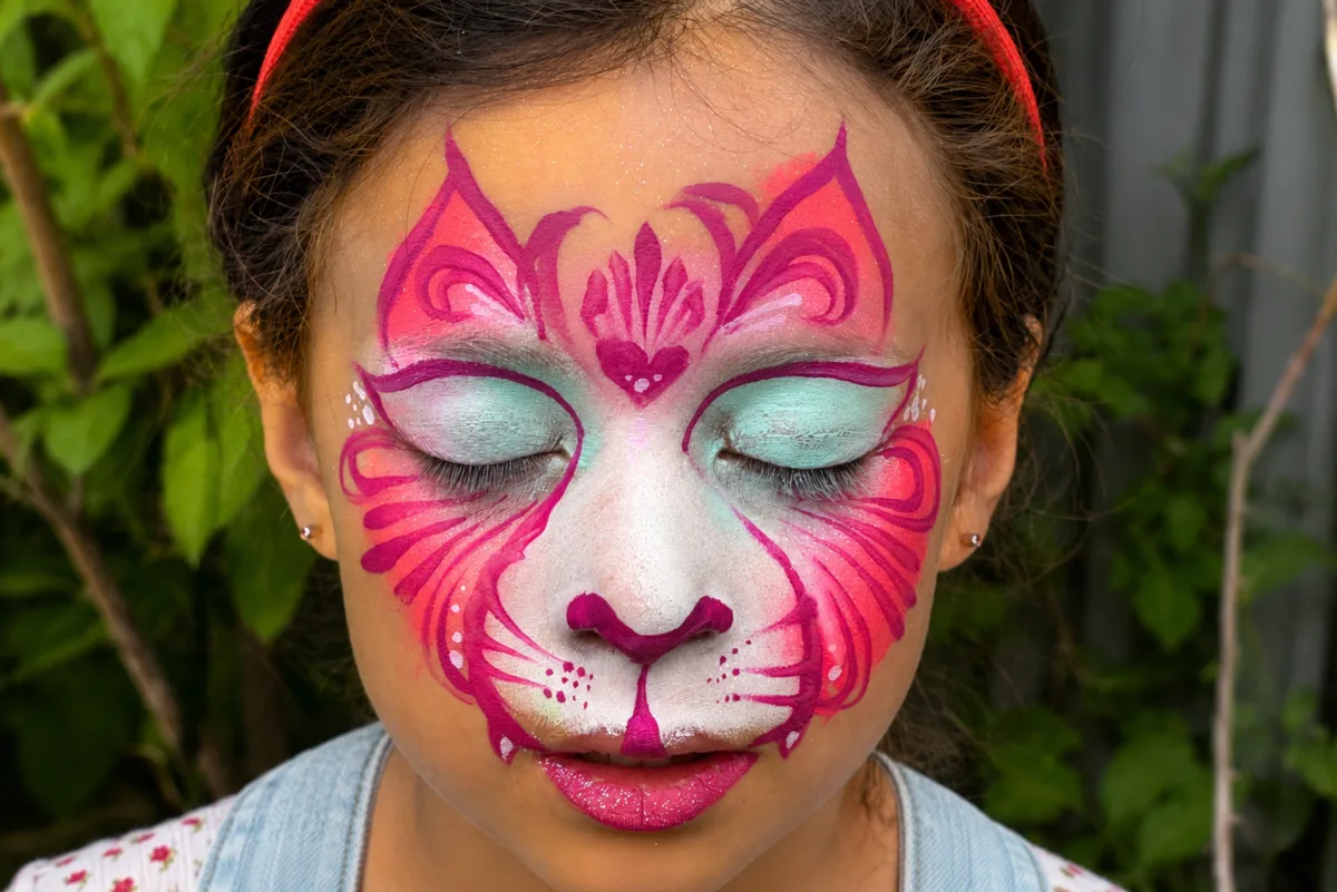 Close-up pink and white face painting design on a child.